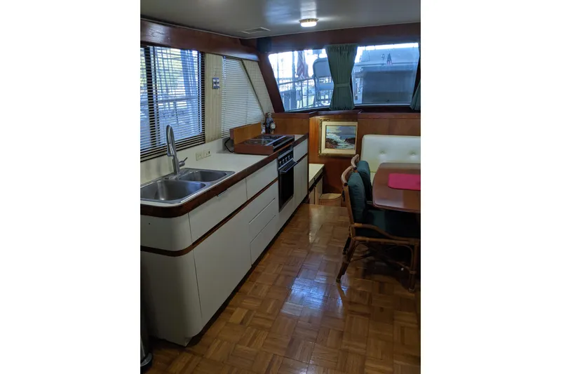 Slide: The Image of 1984 Gulfstar 49 Motor Yacht interior with kitchen and dining area, featuring wood accents and large windows. - 52