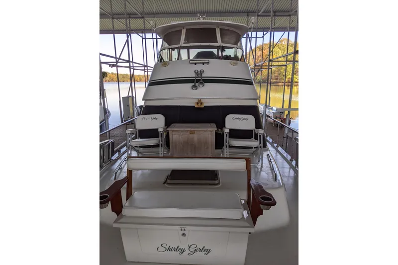 Slide: The Image of 1984 Gulfstar 49 Motor Yacht docked, featuring outdoor seating and scenic lake view. - 96