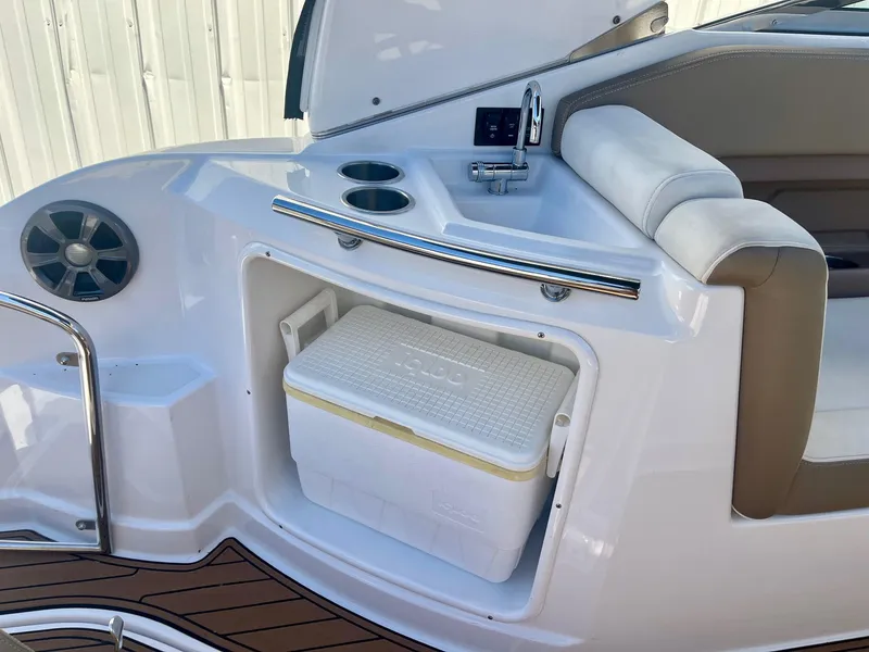 Slide: The Image of 2017 Regal 28 Express boat interior with cooler, sink, and seating area. - 13
