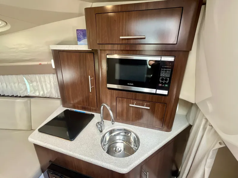 Slide: The Image of 2017 Regal 28 Express boat interior kitchen with microwave, sink, and stove. - 17