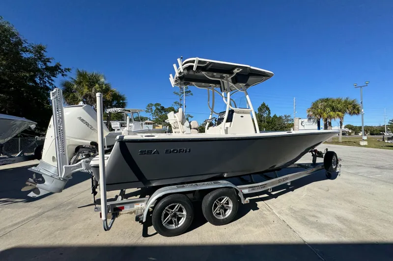 Slide: The Image of 2022 Sea Born LX22 Center Console boat on trailer, parked outdoors under clear blue sky. - 11