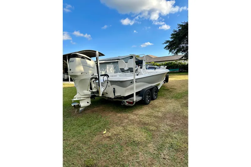 Slide: The Image of 2017 Blue Wave 2400 PureBay boat on trailer, parked on grass under blue sky. - 2