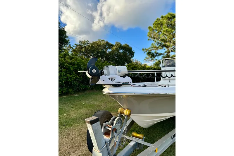 Slide: The Image of 2017 Blue Wave 2400 PureBay boat on trailer, featuring a trolling motor, set against a lush background. - 4