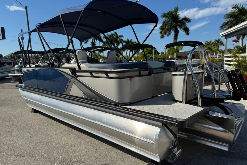 Slide: The Image of 2026 Avalon 2385 LSZ Quad Lounger Tri Toon boat with canopy, parked outdoors. - 8