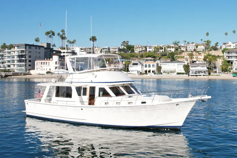 Slide: The Image of 1997 Offshore Yachts 48 Sedan cruising near coastal homes under clear blue skies. - 12