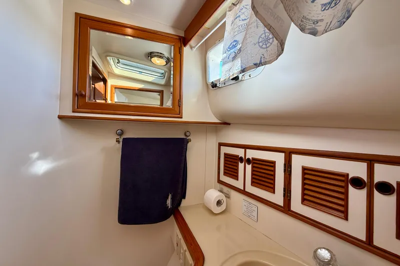 Slide: The Image of Bathroom interior of 1997 Offshore Yachts 48 Sedan with mirror, towel, and cabinets. - 23