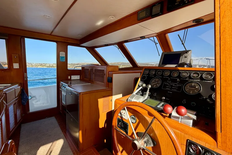Slide: The Image of Interior of a 1997 Offshore Yachts 48 Sedan, featuring a classic wooden helm and navigation equipment. - 37