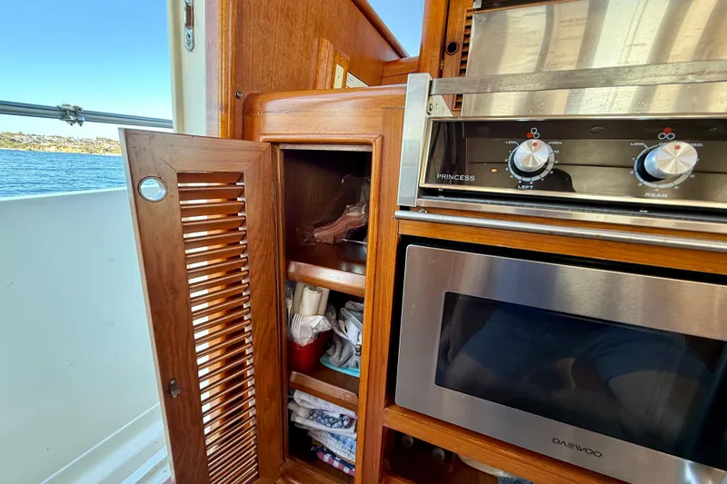 Slide: The Image of Interior of 1997 Offshore Yachts 48 Sedan with wooden cabinetry and kitchen appliances. - 52