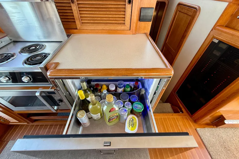 Slide: The Image of Kitchen area of 1997 Offshore Yachts 48 Sedan with open fridge drawer. - 53