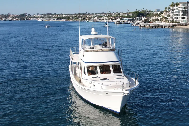 Slide: The Image of 1997 Offshore Yachts 48 Sedan cruising in a scenic coastal harbor. - 6