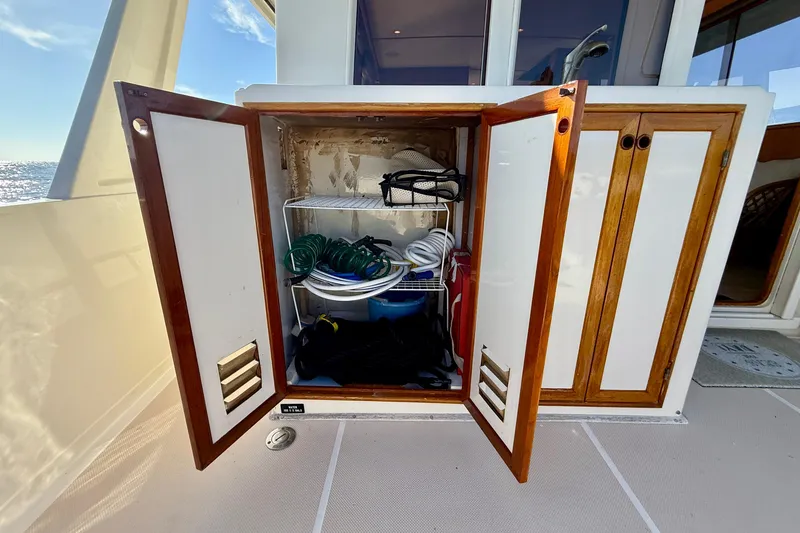 Slide: The Image of Open storage cabinet on 1997 Offshore Yachts 48 Sedan, containing coiled hoses and equipment. - 66