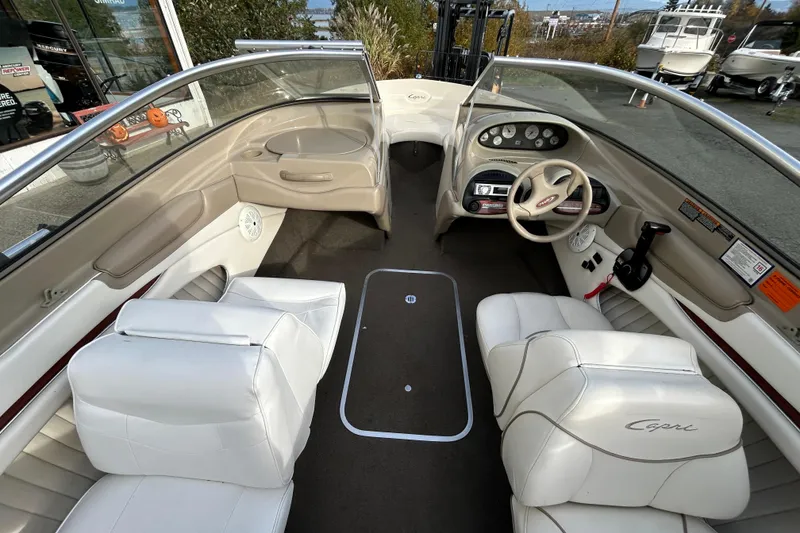 Slide: The Image of 1999 Bayliner 1850 Capri LS boat interior with white seating and dashboard controls. - 2