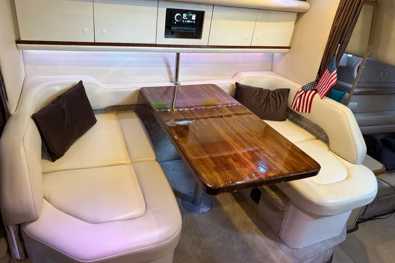 Slide: The Image of 1996 Sea Ray 330 Sundancer cabin with plush seating, wooden table, and American flag decor. - 10