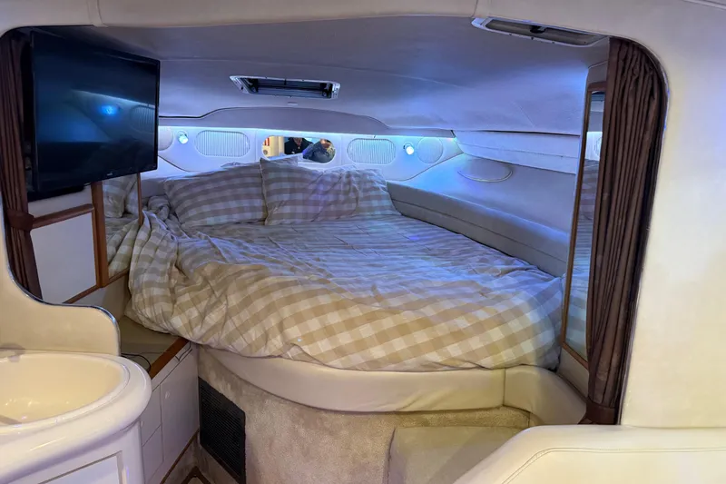 Slide: The Image of 1996 Sea Ray 330 Sundancer cabin with bed, TV, and sink, featuring cozy interior design. - 12
