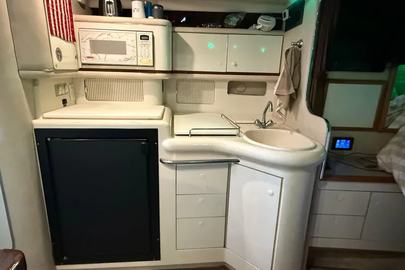 Slide: The Image of 1996 Sea Ray 330 Sundancer cabin kitchen with sink, microwave, and storage cabinets. - 14