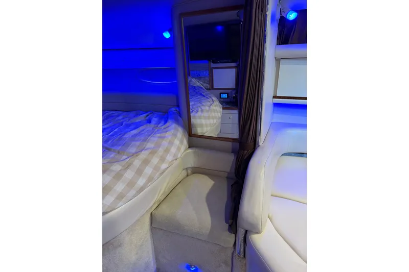 Slide: The Image of 1996 Sea Ray 330 Sundancer cabin interior with blue lighting and cozy bedding. - 8