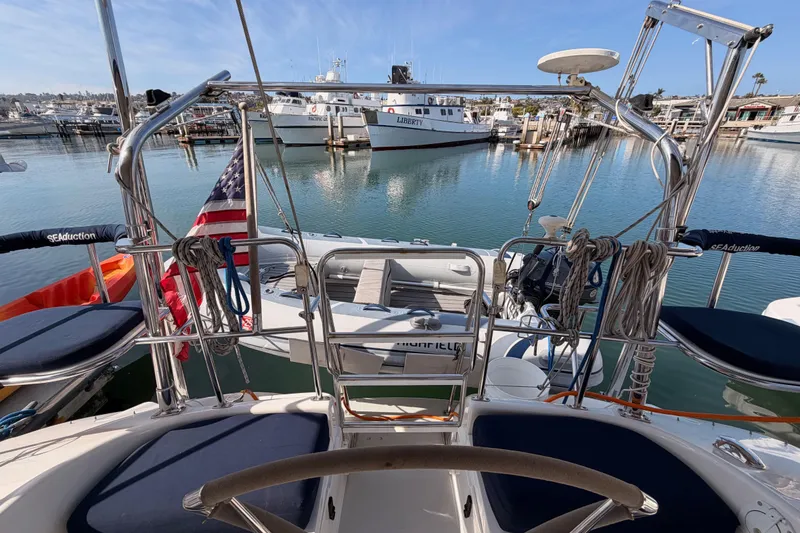 Slide: The Image of 2005 Catalina 42 MkII sailboat docked in marina, featuring American flag and nautical equipment. - 23