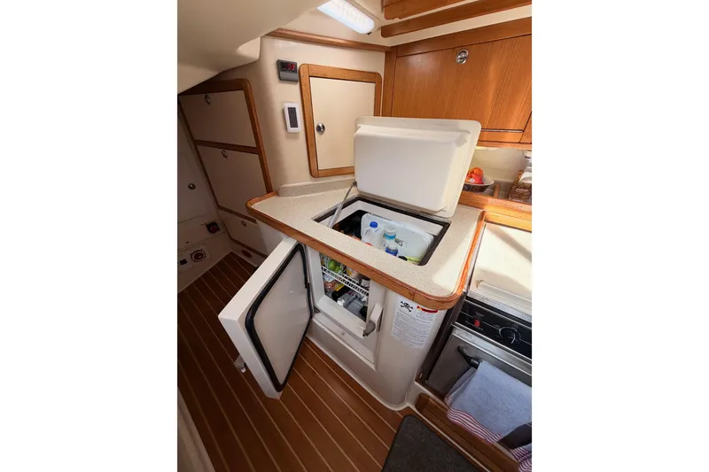 Slide: The Image of Interior of 2005 Catalina 42 MkII yacht galley with open fridge and wooden cabinetry. - 42