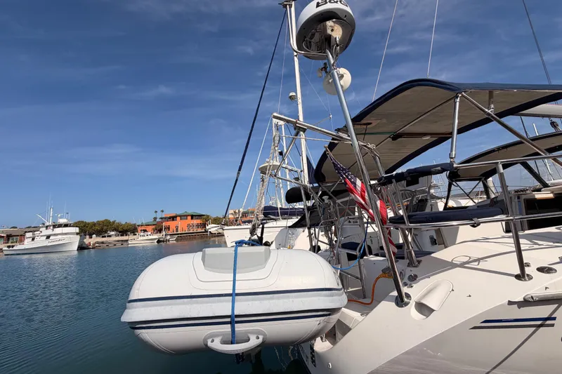 Slide: The Image of Catalina 42 MkII 2005 sailboat docked with dinghy, clear sky, marina background. - 7