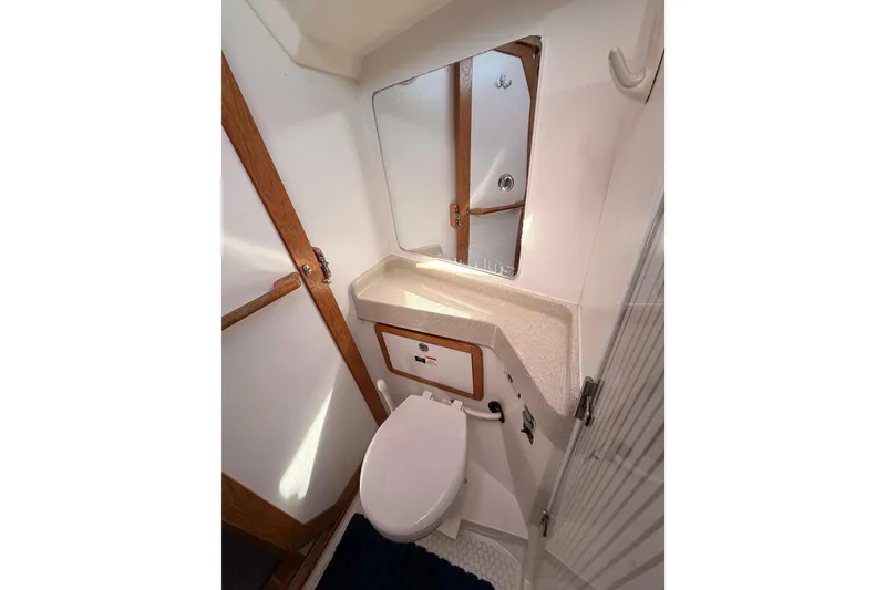 Slide: The Image of Bathroom interior of 2005 Catalina 42 MkII yacht, featuring a compact toilet and mirror. - 73