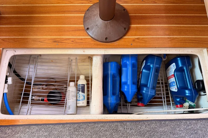 Slide: The Image of Storage compartment on a 2005 Catalina 42 MkII sailboat with blue containers and cleaning supplies. - 82
