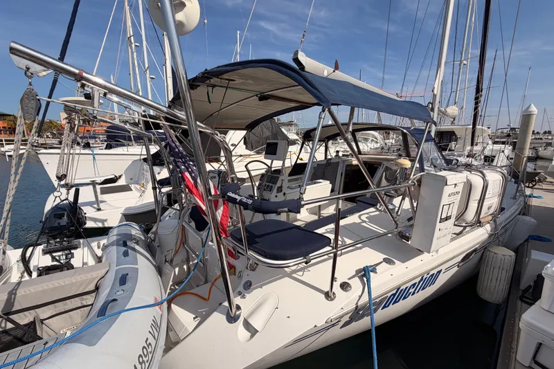 Slide: The Image of 2005 Catalina 42 MkII sailboat docked at marina, featuring blue canopy and American flag. - 9