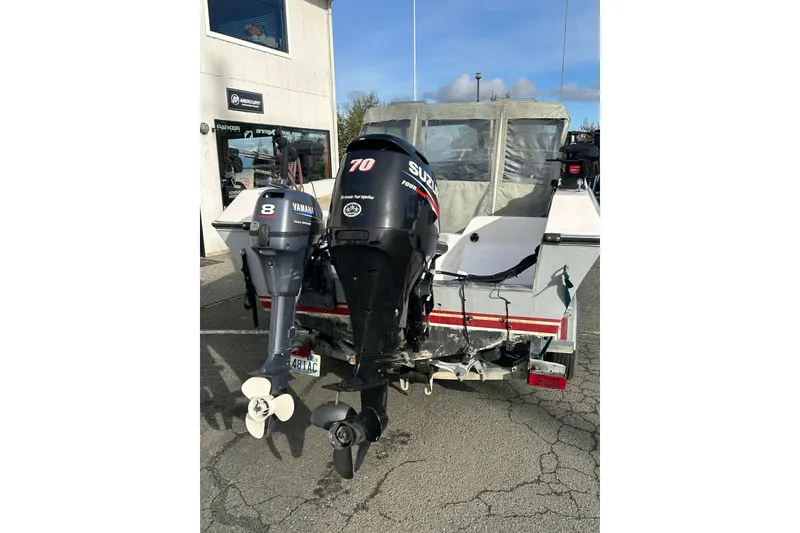 Slide: The Image of 1989 Olympic 17 Cabin boat with Yamaha and Suzuki outboard motors, parked outside a dealership. - 4