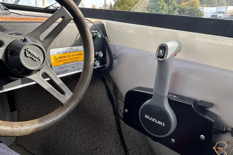 Slide: The Image of Interior of 1989 Olympic 17 Cabin boat with steering wheel and Suzuki throttle control. - 8