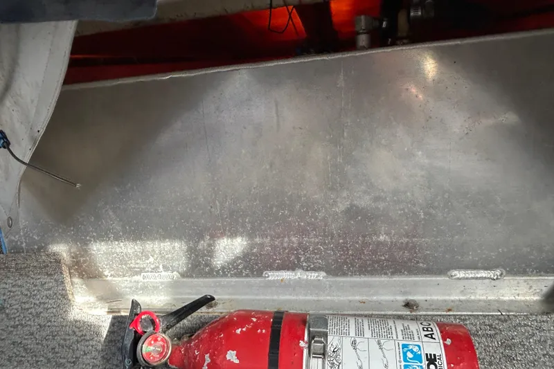 Slide: The Image of Fire extinguisher in 1989 Olympic 17 Cabin boat interior, near metal panel and carpeted floor. - 9