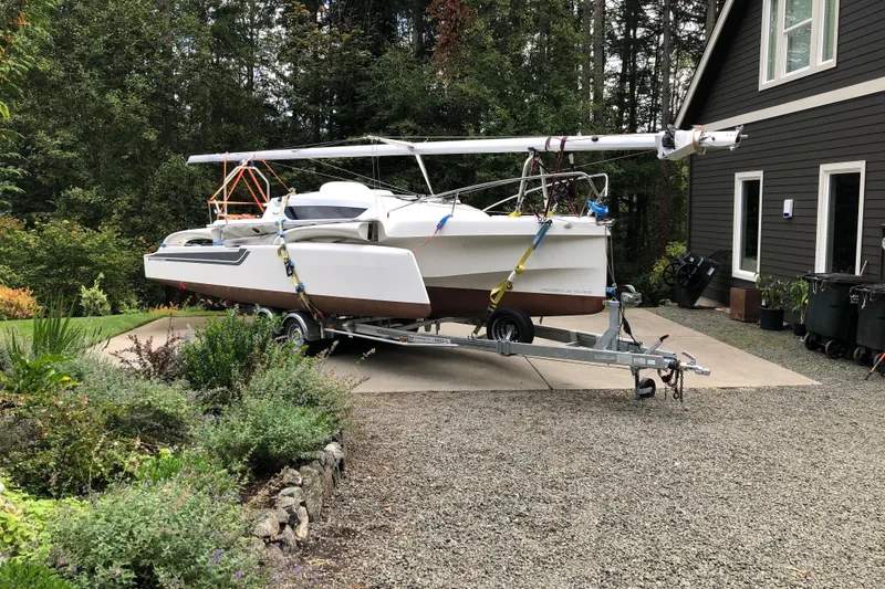 The Image of 2022 Dragonfly 25 sailboat on trailer in driveway, surrounded by greenery. - 0