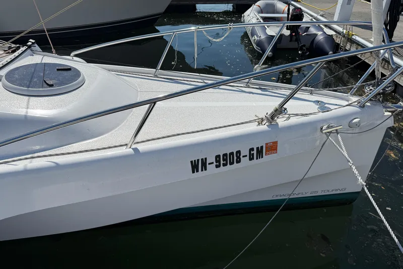 Slide: The Image of Sailboat Dragonfly 25, 2022 model, docked with visible registration number. - 7