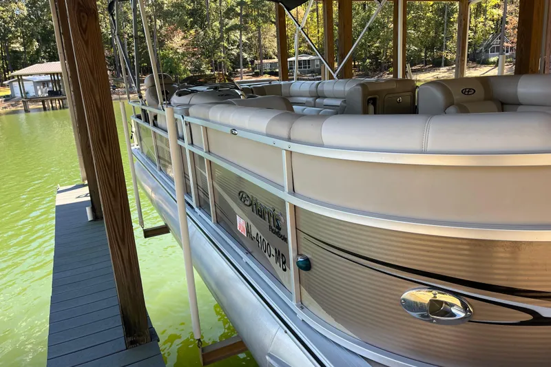 Slide: The Image of 2010 Harris FloteBote 220 Sunliner pontoon boat docked on a serene lake. - 1
