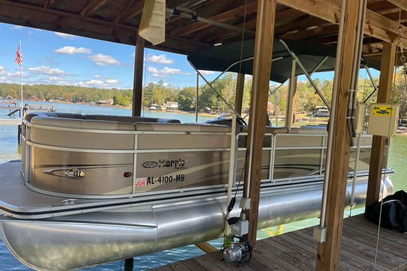 Slide: The Image of 2010 Harris FloteBote 220 Sunliner pontoon boat docked on a serene lake. - 3