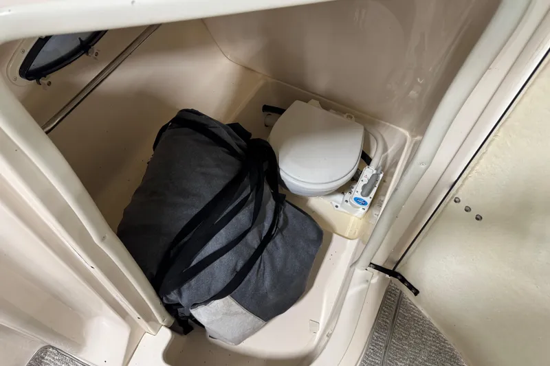 Slide: The Image of 2004 Rinker 282 BR boat interior with portable toilet and storage bag. - 11
