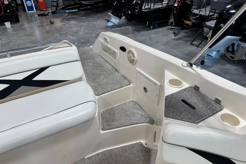 Slide: The Image of 2004 Rinker 282 BR boat interior with seating, cup holders, and carpeted flooring. - 13