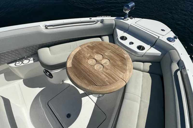Slide: The Image of 2022 Sea Ray SLX 400 Outboard boat interior with wooden table and cushioned seating. - 50