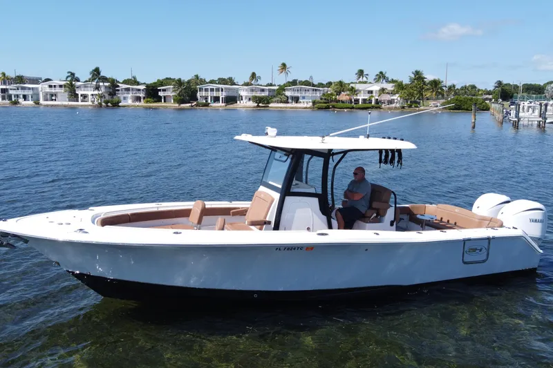 The Image of 2022 Sea Hunt Ultra 305 SE boat on calm water near waterfront homes. - 0