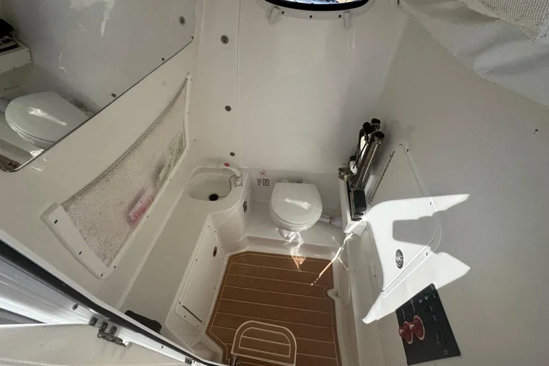 Slide: The Image of Interior of 2022 Sea Hunt Ultra 305 SE boat, featuring a compact bathroom with toilet and sink. - 18