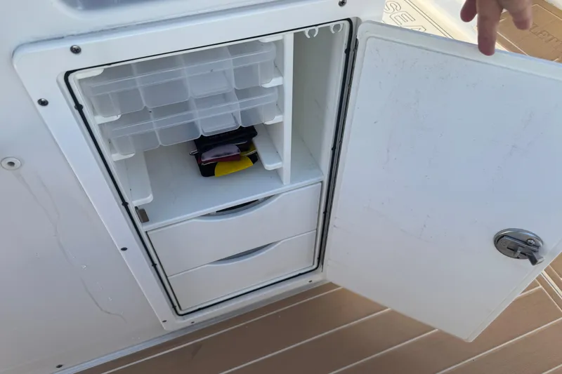 Slide: The Image of Open storage compartment on 2022 Sea Hunt Ultra 305 SE boat, featuring organized shelves and drawers. - 24