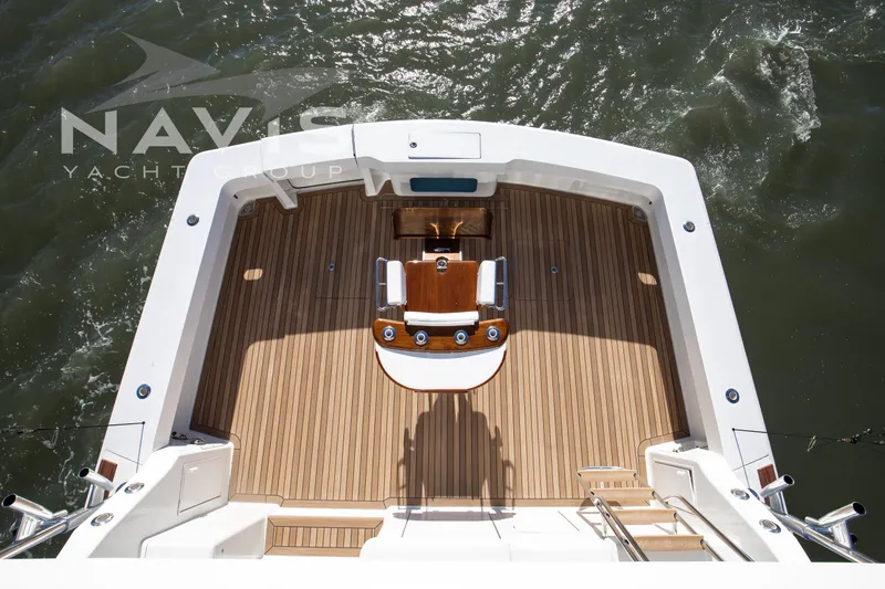 Slide: The Image of 1998 Viking 58 Convertible yacht deck with seating and fishing setup on calm water. - 20