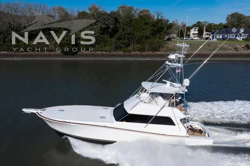Slide: The Image of 1998 Viking 58 Convertible yacht cruising on a scenic waterway under a clear blue sky. - 9