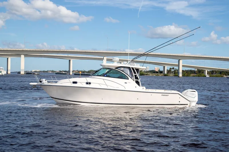 The Image of 2013 Pursuit OS 345 Offshore boat cruising under a bridge on a sunny day. - 0