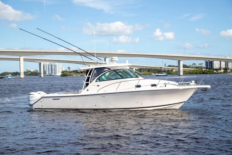 Slide: The Image of 2013 Pursuit OS 345 Offshore boat cruising on a river with a bridge in the background. - 2