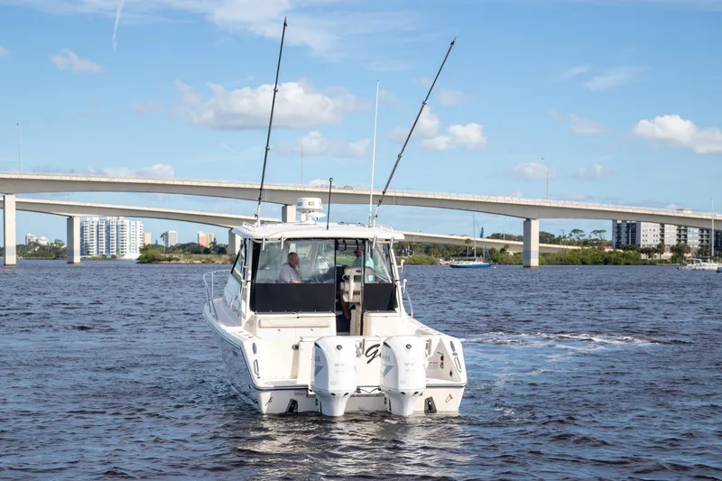 Slide: The Image of 2013 Pursuit OS 345 Offshore boat cruising under a bridge on a sunny day. - 3