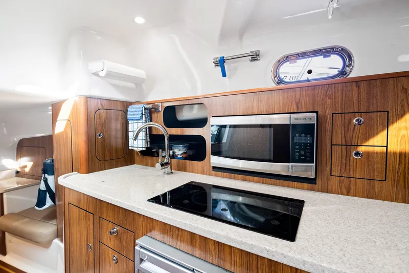 Slide: The Image of 2013 Pursuit OS 345 Offshore yacht interior kitchen with wood cabinetry and modern appliances. - 6