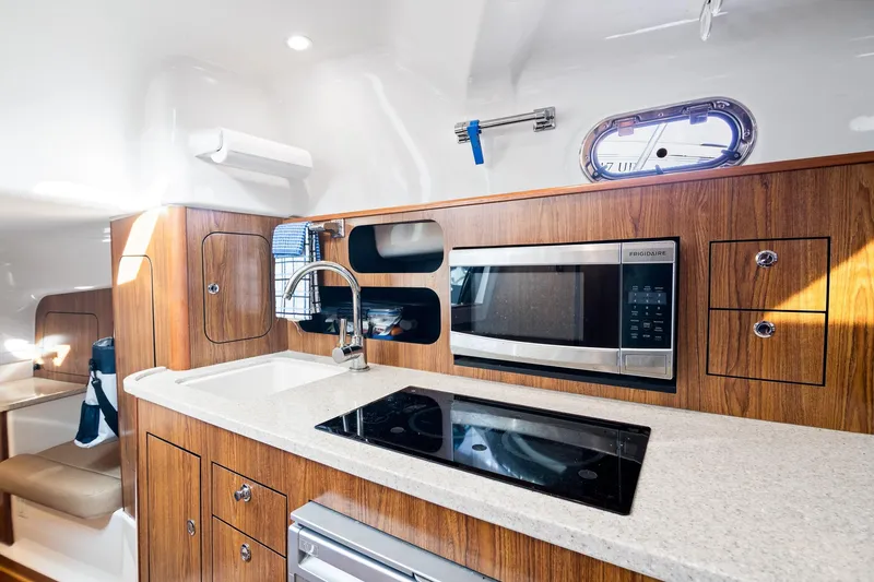 Slide: The Image of 2013 Pursuit OS 345 Offshore yacht kitchen with wood cabinetry, microwave, and stovetop. - 8