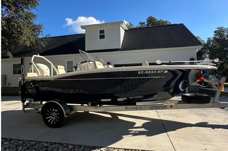 Slide: The Image of 2025 Scout 195 Sport Dorado boat on trailer, parked in driveway under clear blue sky. - 5