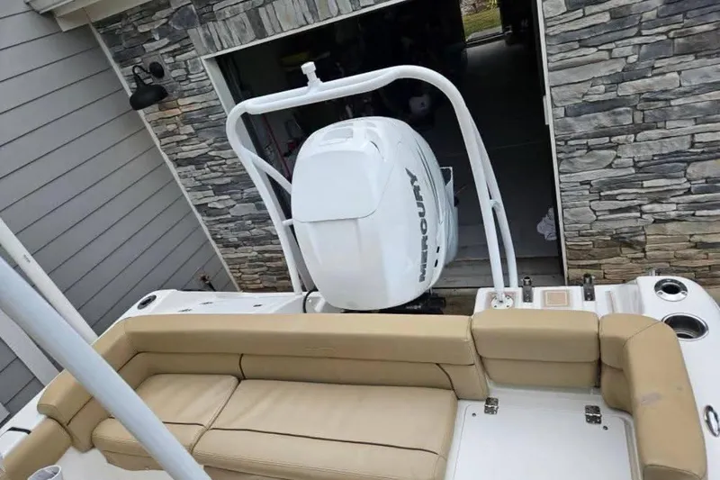 Slide: The Image of 2015 Tidewater 230 LXF boat with Mercury engine, beige seating, and stone wall background. - 8