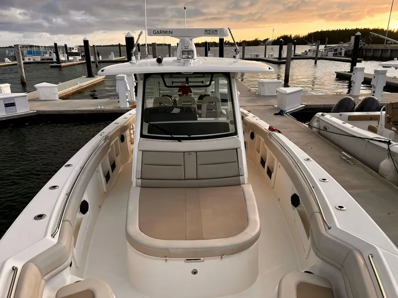 Slide: The Image of 2019 Boston Whaler 380 Outrage at marina, sunset view, showcasing spacious deck and seating. - 12