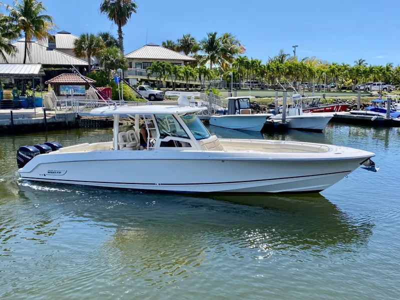 Slide: The Image of 2019 Boston Whaler 380 Outrage boat docked in a sunny marina setting. - 2